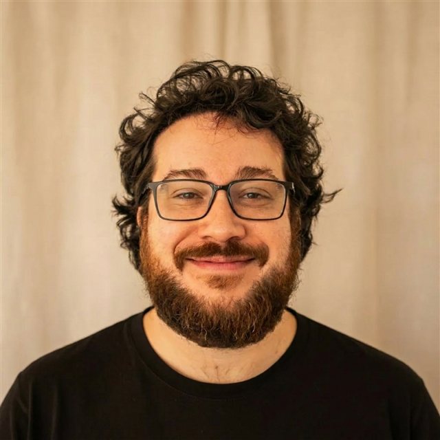 Retrato de Matheus Jorge sorrindo, de óculos e camiseta preta